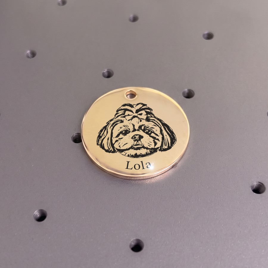El láser grabando el retrato y el nombre de Lola en un dije dorado
